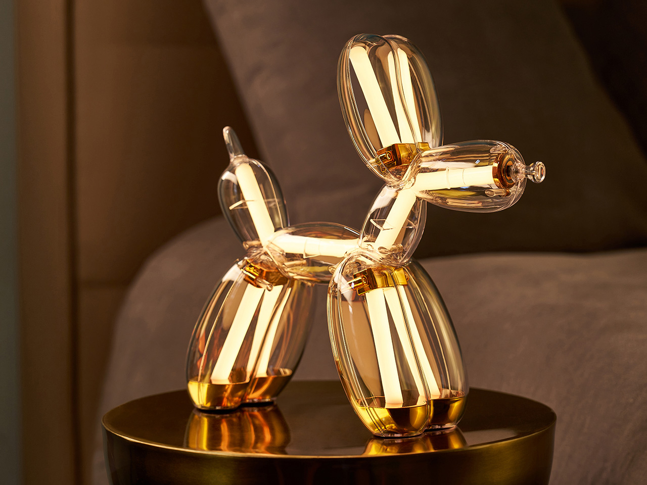 Illuminated Balloon Dog Lamp Chromatic in transparent gold polycarbonate, featuring integrated LED lighting and reflective sculptural form. Official Jeff Koons x Lexon collaboration, presented by Designooor Media and Academy. Written and edited by Hamed Mahzoon 